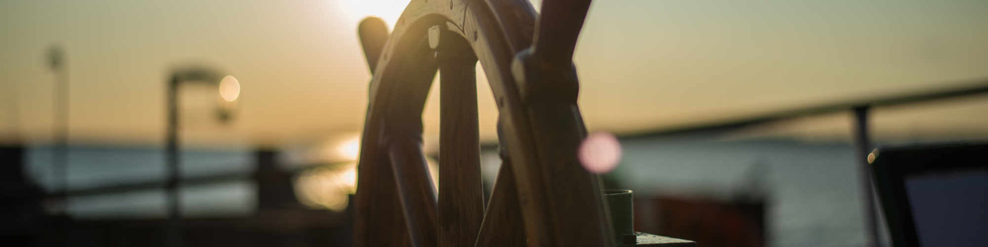 Blog banner 2000x500pxls Image of a boat's steering wheel